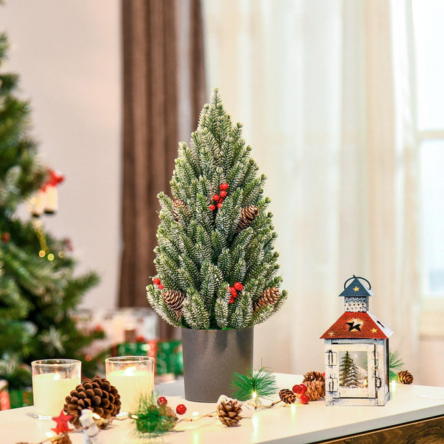 Schneebedeckter Tischweihnachtsbaum mit Beeren und Tannenzapfen